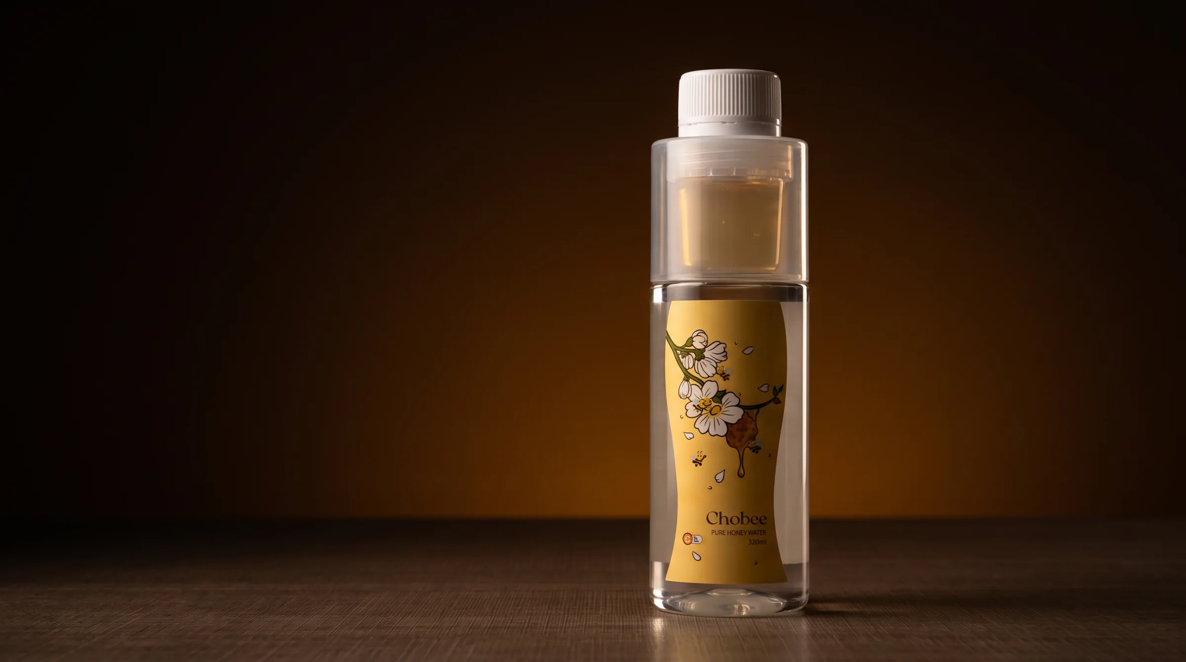 A bottle of CHOBEE Pure Honey Water lit against a deep amber backdrop